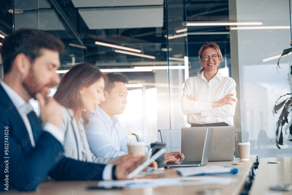 Smiling confident businesswoman on business meeting with colleagues in office . Blurred background Smiling confident businesswoman on business meeting with colleagues in office . Blurred background