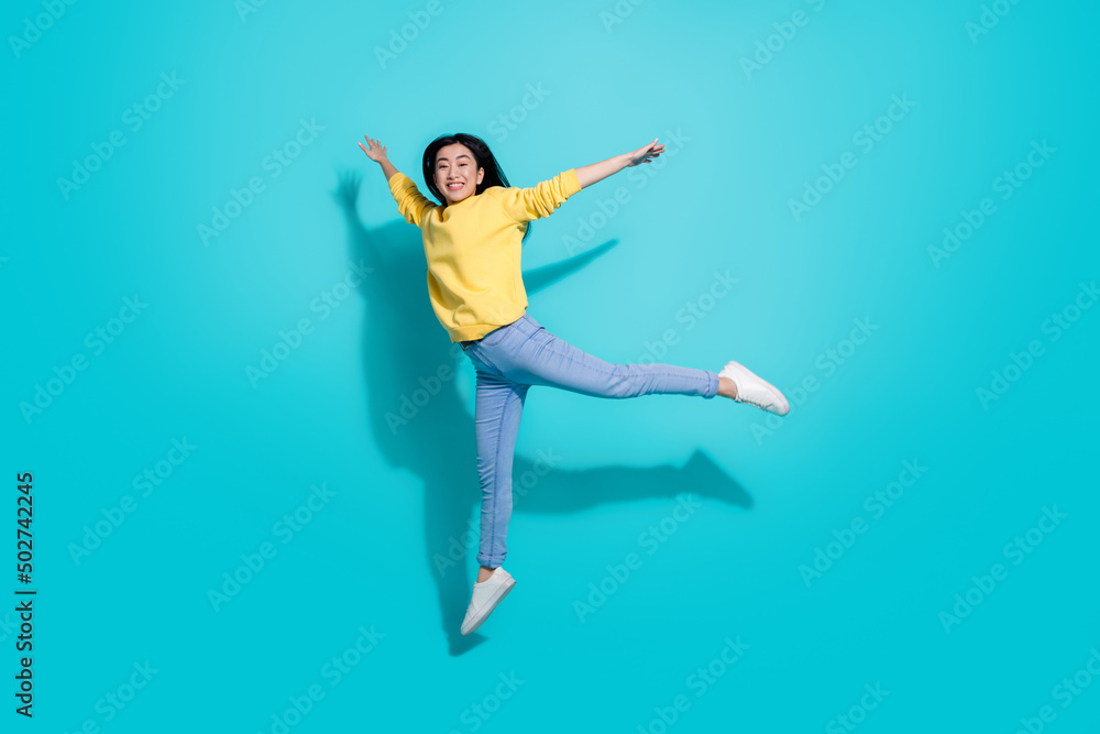 Full length photo of cute charming lady dressed yellow sweater jumping high dancing isolated turquoise color background Full length photo of cute charming lady dressed yellow sweater jumping high dancing isolated turquoise color background