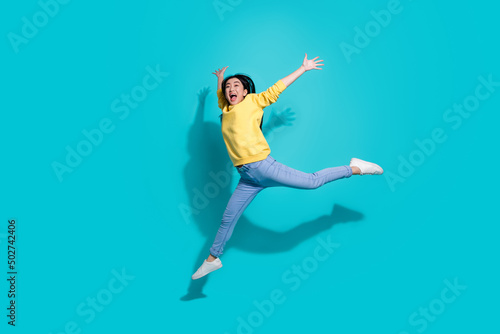 Full length photo of pretty sweet lady dressed yellow sweater jumping dancing empty space isolated turquoise color background © deagreez