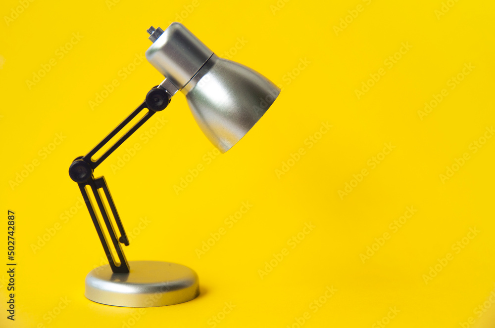 Closeup silver and black small lamp on yellow color background. Copy space concept Closeup silver and black small lamp on yellow color background. Copy space concept