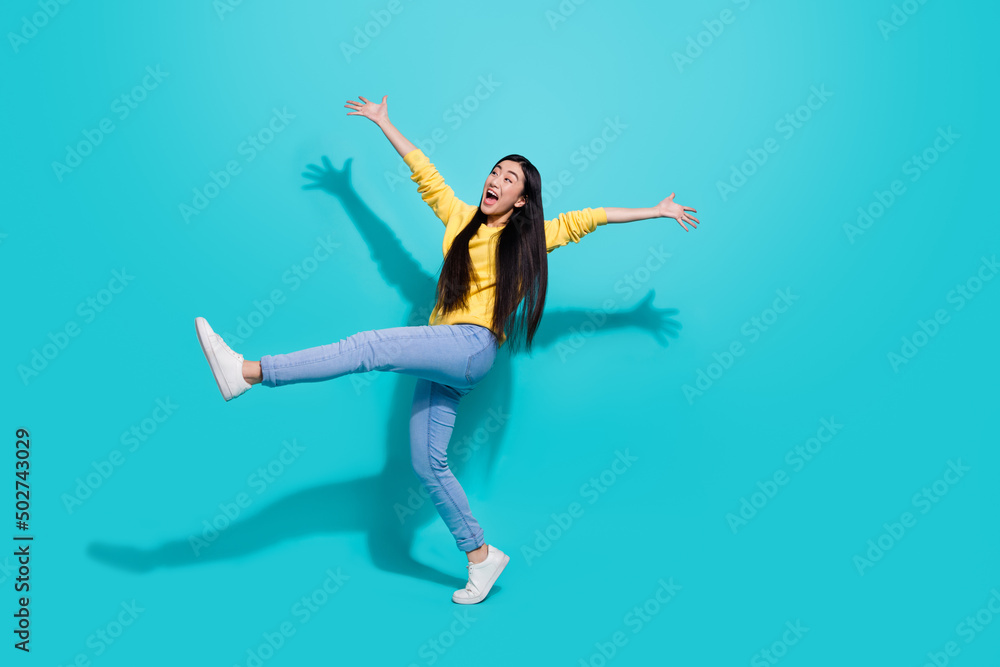 Full length photo of impressed funky lady dressed yellow sweater dancing walking empty space isolated turquoise color background
