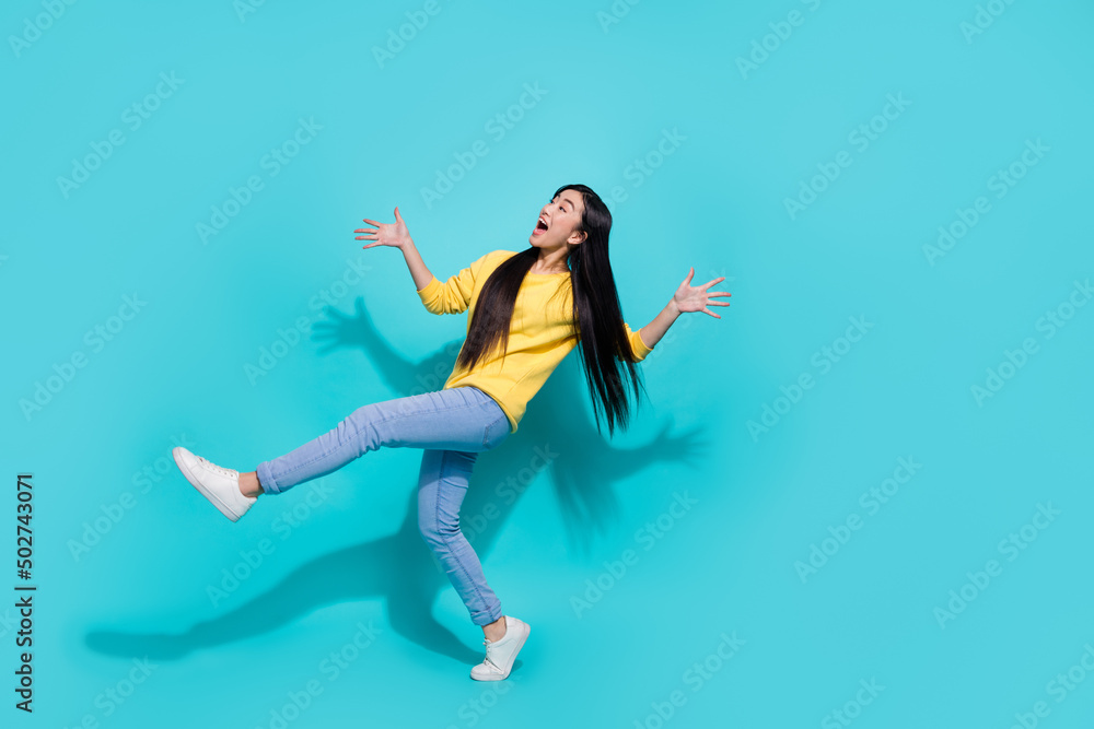 Full length photo of pretty impressed lady dressed yellow sweater dancing looking empty space isolated turquoise color background
