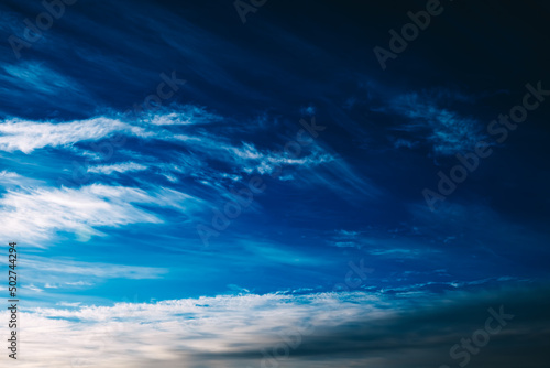 Foto White spindrift clouds moving fast in dark blue sky