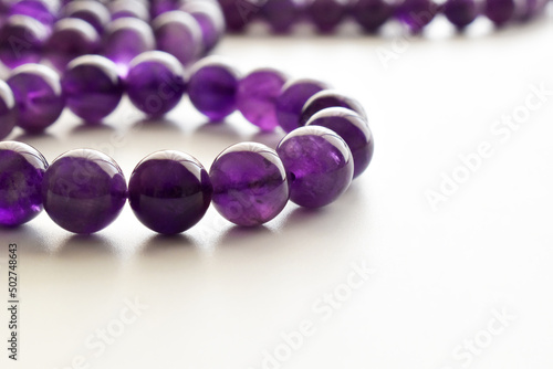 Amethyst gemstone bracelet on the table. Purple or violet crystal stone on white background.