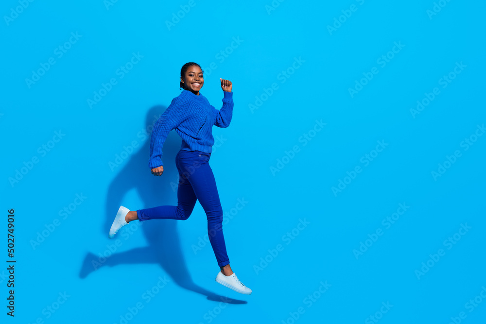 Full length body size view of attractive cheerful girl jumping running copy space action isolated over bright blue color background Full length body size view of attractive cheerful girl jumping running copy space action isolated over bright blue color background
