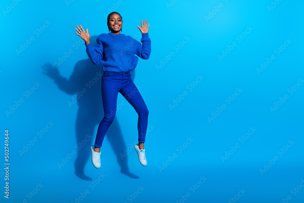 Photo of charming excited woman wear sweatshirt jumping high empty space isolated blue color background