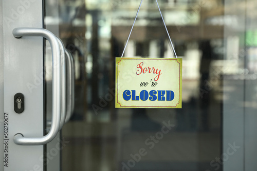 Yellow sign with text Sorry we're Closed hanging on glass door. Coronavirus quarantine