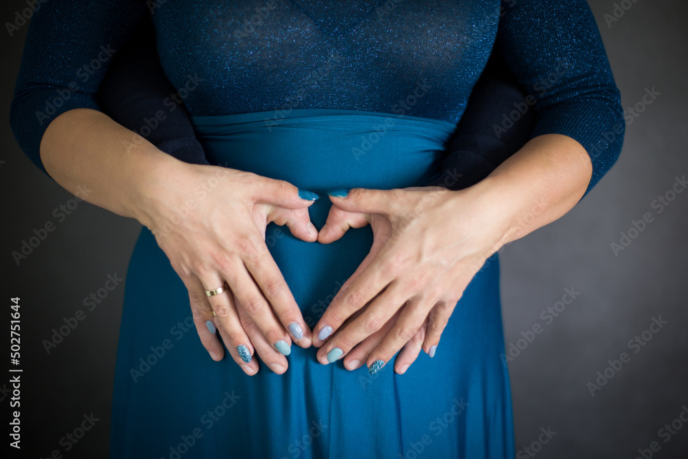 9 miesięcy ciąży, kobieta i mężczyzna trzymają ręce w kształcie serca na brzuchu ciążowym - obrazy, fototapety, plakaty 
