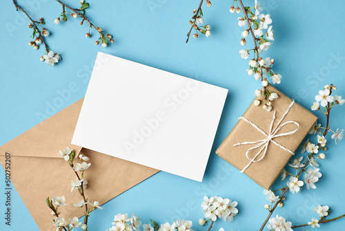 Greeting card mockup with gift and white flowers on blue