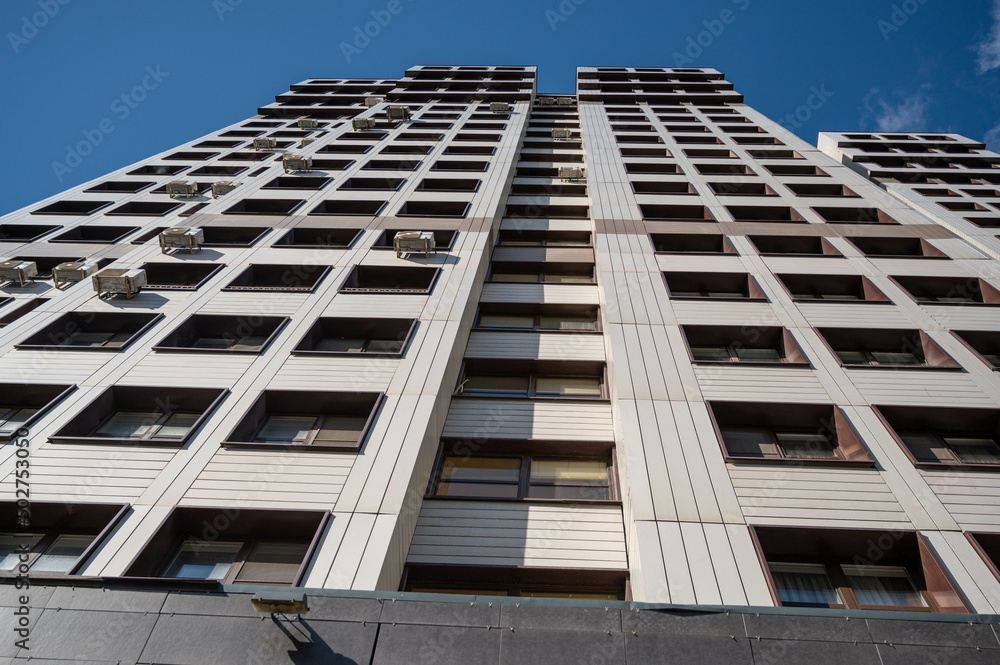 Facade of a tall residential building from the bottom up. The perspective of the house stretching into the sky Facade of a tall residential building from the bottom up. The perspective of the house stretching into the sky