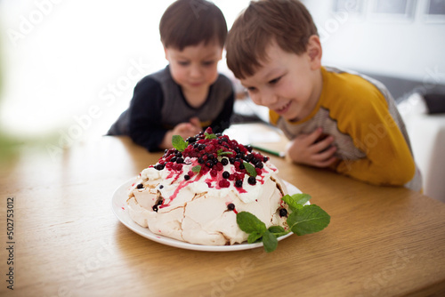 Beza z owocami lata i miętą, pyszne ciastko zjadane przez dzieci, chłopcy podziwiają domowe wypieki