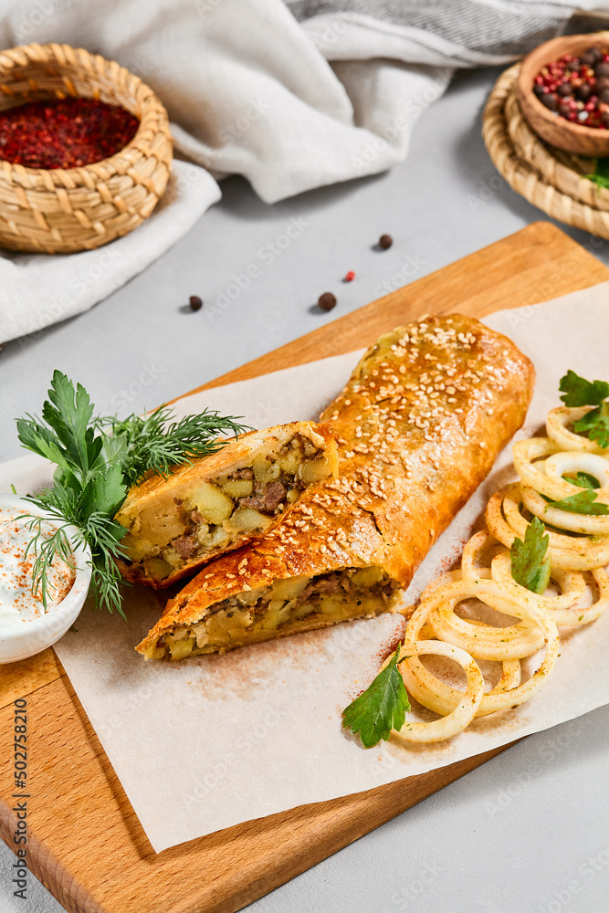 Meat pie with greens and onion on wood plate. Eastern food - beef pie with sesame. Eastern pastry with Minced meat. Meat pie with greens and onion on wood plate. Eastern food - beef pie with sesame. Eastern pastry with Minced meat.