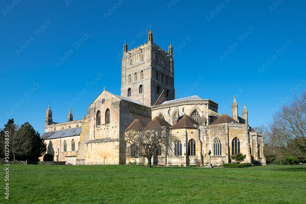 Fototapeta premium A low wide angle image of Tewkesbury Abbey with the beautiful green grass foreground and clear blue skies.