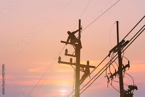 silhouette electrician working on high voltage pole install equipment 