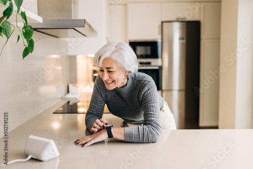 Senior woman using smart devices in her kitchen at home