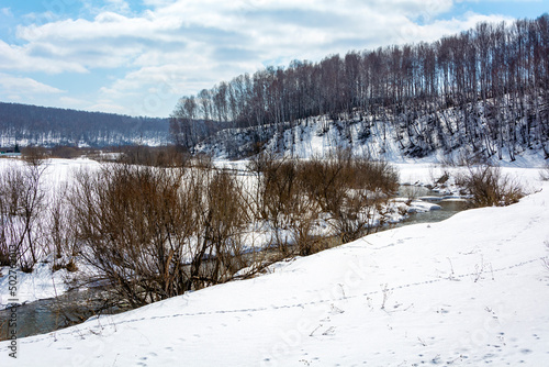 View of the Bolshaya Podikova River in spring with snow-covered banks