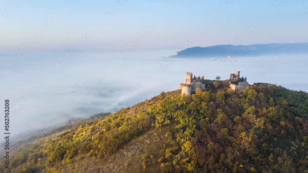 the ruins of a medieval castle at sunrise over the fog