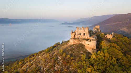 the ruins of a medieval castle at sunrise over the fog