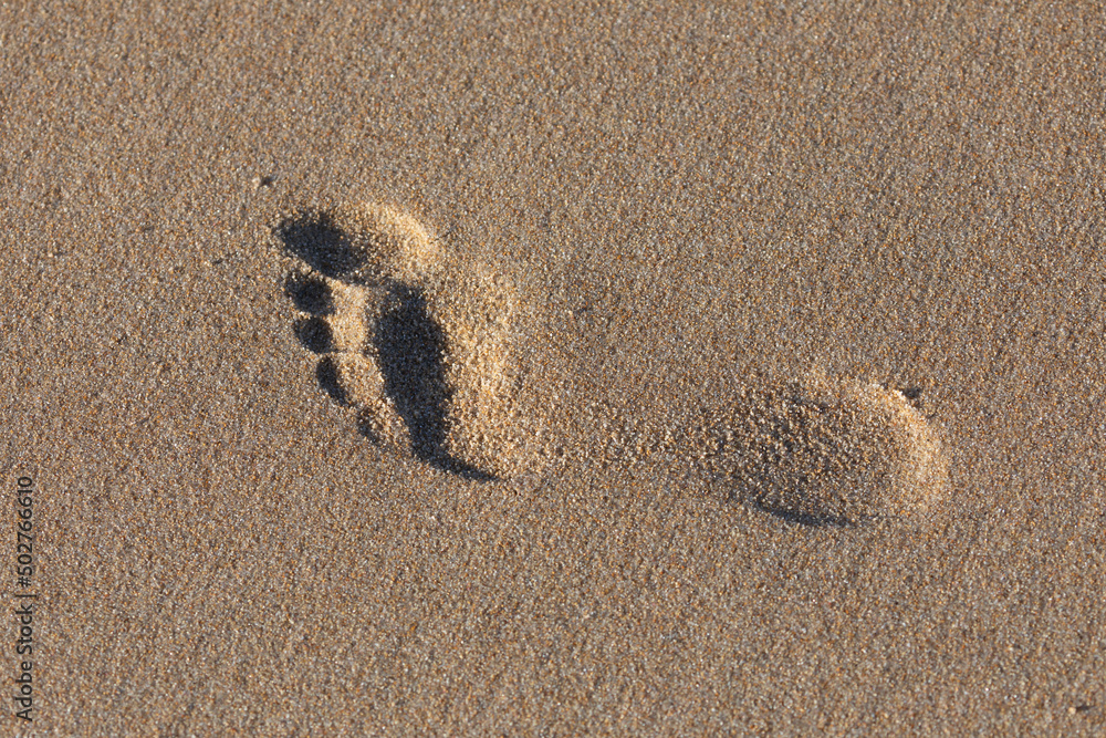 The footprint of a person in the sand of the beach, forms a relief full ...