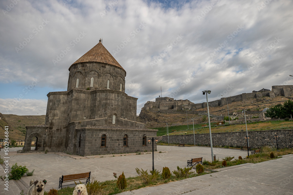 Ancient stone bridge across Kars River & Kars Castle - main tourist attractions of Kars, Turkey. Near flag (on castle) are portrait of Ataturk & writing in Turkish 'Motherland remembers you'