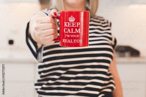 person holding a mug that says keep calm i'm your realtor red  photo