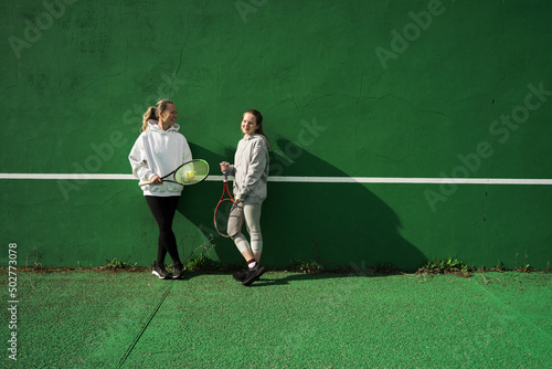 Mother and her teen daughter talking with each other on the tennis court