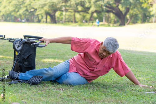 Asian senior man falling down from wheelchair on lying floor after trying push the wheelchair forward and Crying in pain and asking someone for help. Concept of old elderly insurance and health care