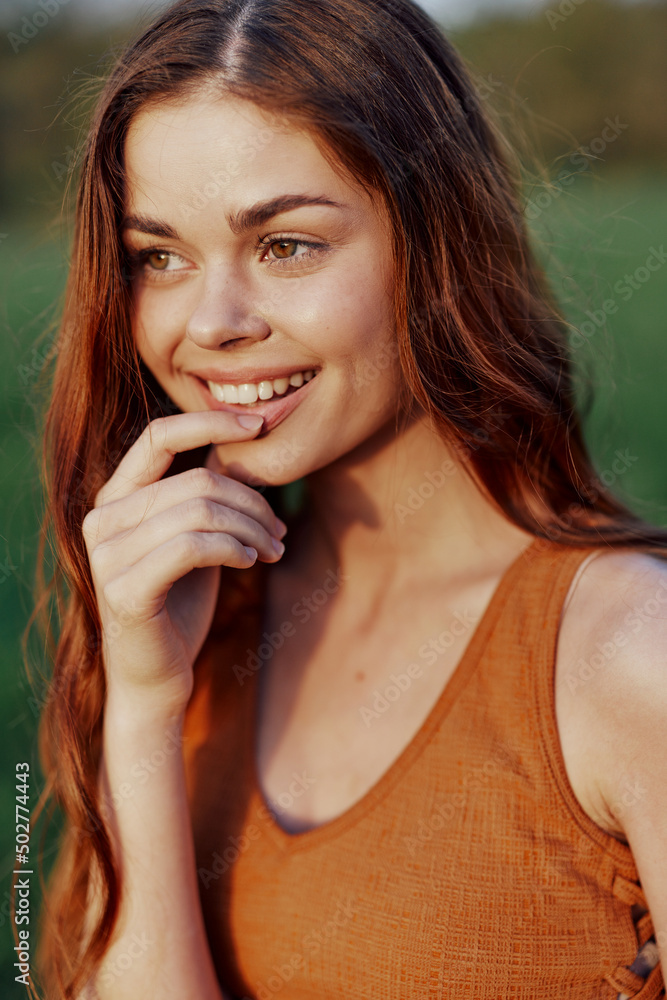 Close-up portrait of a smiling young woman in the sun with red hair in nature Close-up portrait of a smiling young woman in the sun with red hair in nature