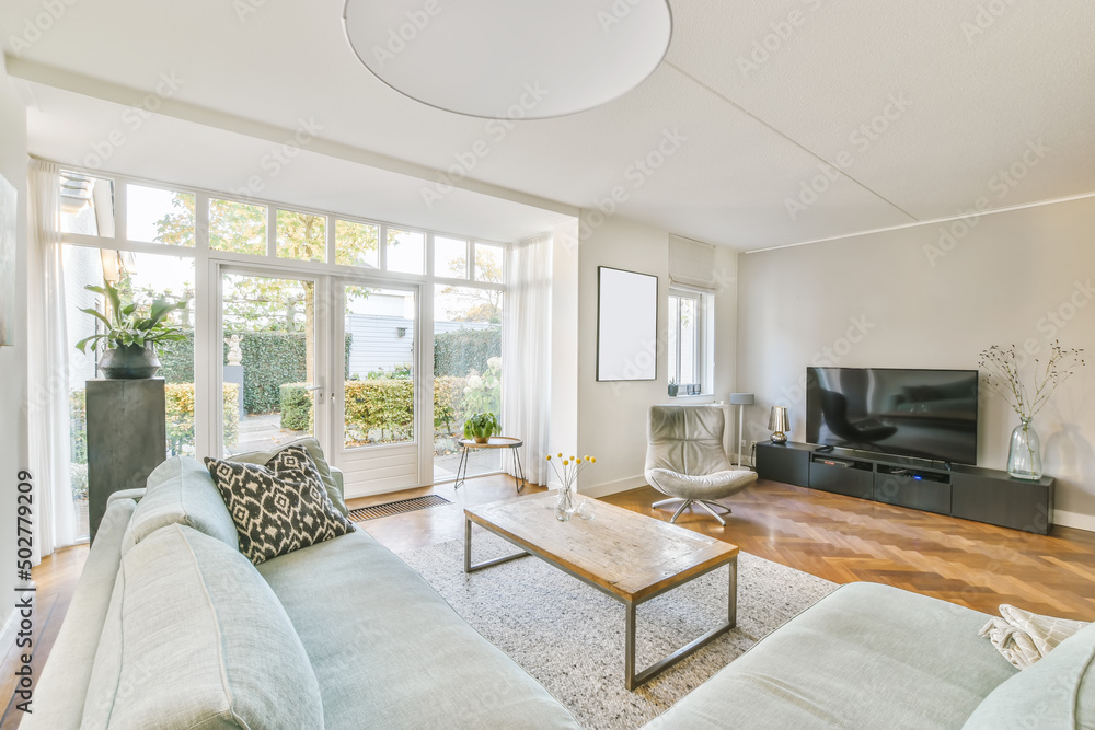 Spacious living room with corner sofa and modern TV set in daylight Spacious living room with corner sofa and modern TV set in daylight