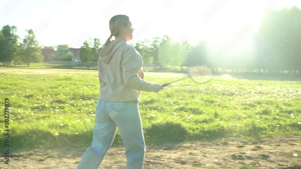 Young woman playing badminton, active games in summer in nature Young woman playing badminton, active games in summer in nature
