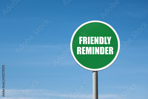 'Friendly reminder' sign in green round frame. Clear blue sky is on background