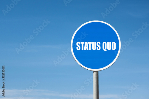 'Status quo' sign in blue round frame. Clear sky is on background