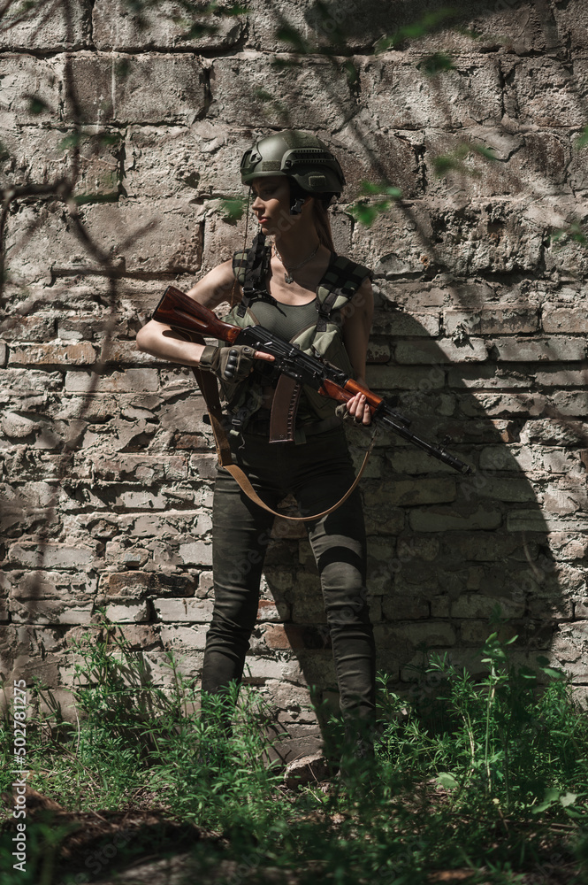 Fototapeta premium Military girl in uniform near a stone wall during the day