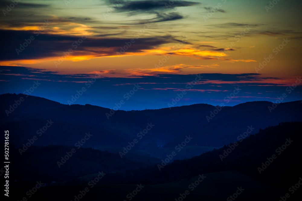 Twilight, night sky. End of the day, when the sun goes down. Early evening, colorful sky, blue, orange, afternoon. Mountains, clouds, Brazilian landscape at night. Glow of light at the horizon.