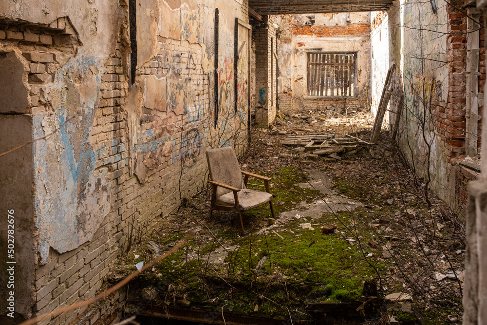 Abandoned house. Moss grows inside. Everything is broken and destroyed. An old armchair in the center of the room