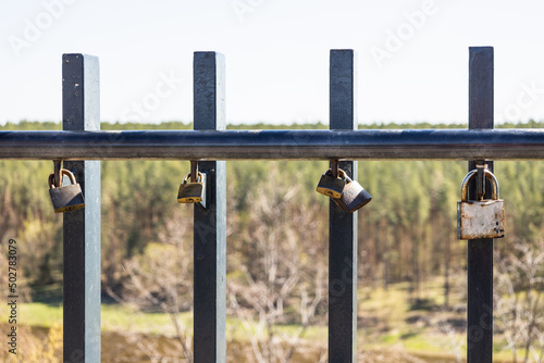 Closeup view of love padlocks hanging on a bridge fence