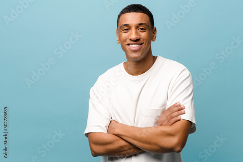 Vászonkép Smiling young African-american man in white casual t-shirt standing with crossed