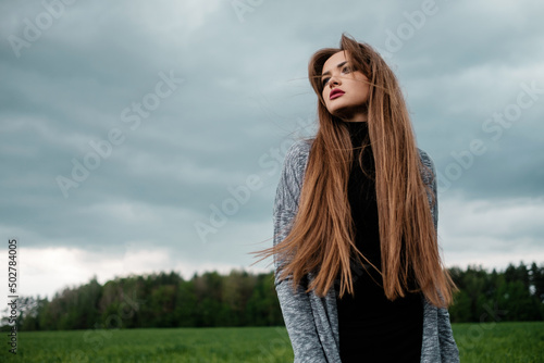 Girl with long hair standing in field in the wind. The concept of freedom and passion.
