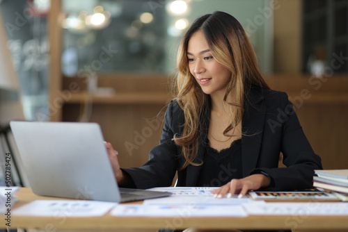 Portrait of a business woman working or secretary with laptop and financial documents on the desk in the office.