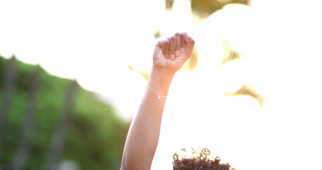 African American woman raises fist in air in political movement, black person activist