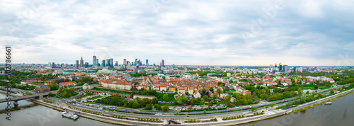 Historyczna panorama miasta z widokiem pod dużym kątem na kolorowe dachy budynków na rynku starego miasta. W tle widok na centrum nowoczesnej Warszawy z sylwetkami drapaczy chmur. © hunter76