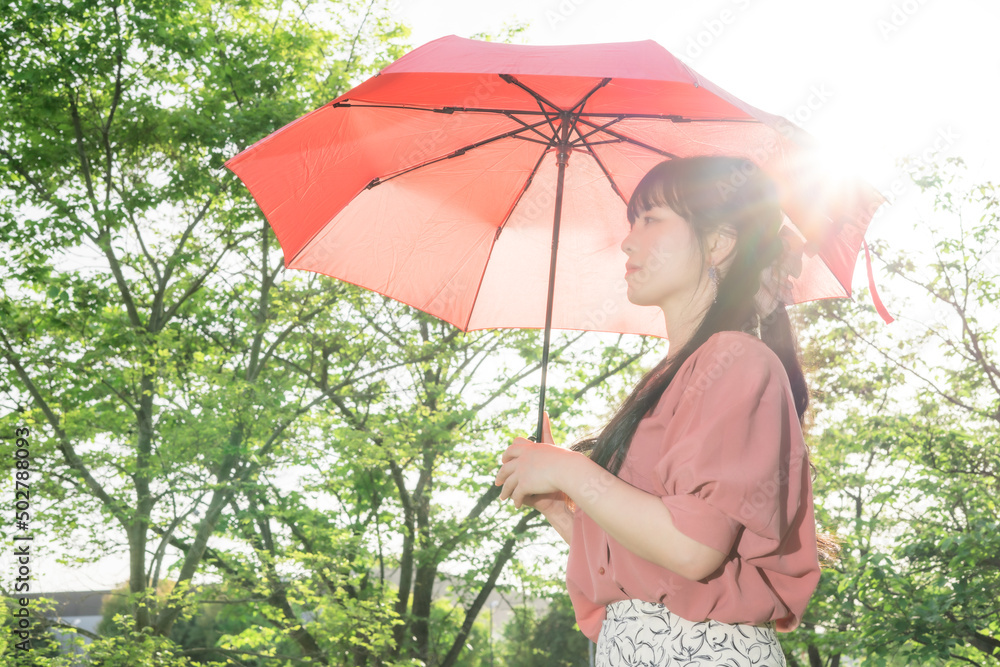 強い日差しの中で赤い日傘をさす女性 Stock-Foto | Adobe Stock