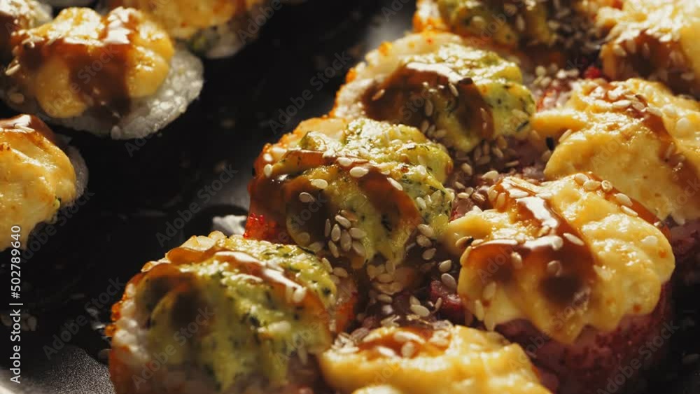 Rolls baked with cheese cream in teriyaki sauce and sesame seeds on a wooden board close-up. Vertical panorama Rolls baked with cheese cream in teriyaki sauce and sesame seeds on a wooden board close-up. Vertical panorama
