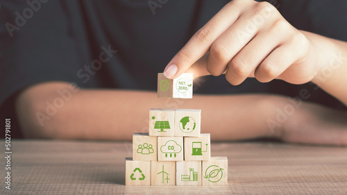 Net zero and carbon neutral concept. Net zero greenhouse gas emissions target No toxic gases. Hand Put wooden cubes with green net zero icon and green icon