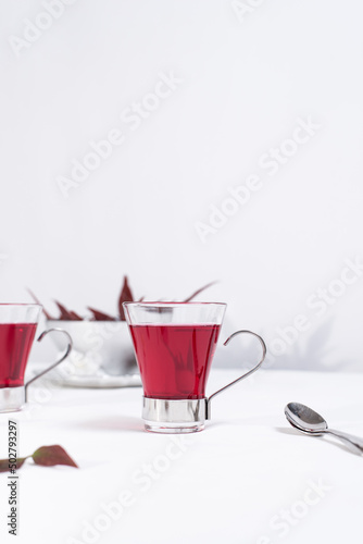 Dos tazas transparente de té de bayas sobre una mesa blanca y un fondo gris claro	