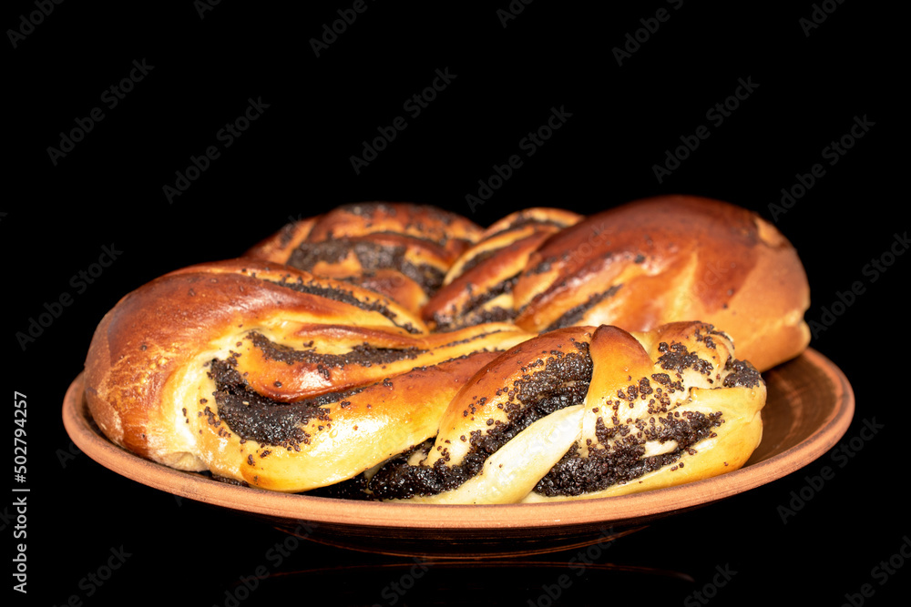 Two fragrant buns with poppy seeds on a ceramic plate, close-up, isolated on a black background.