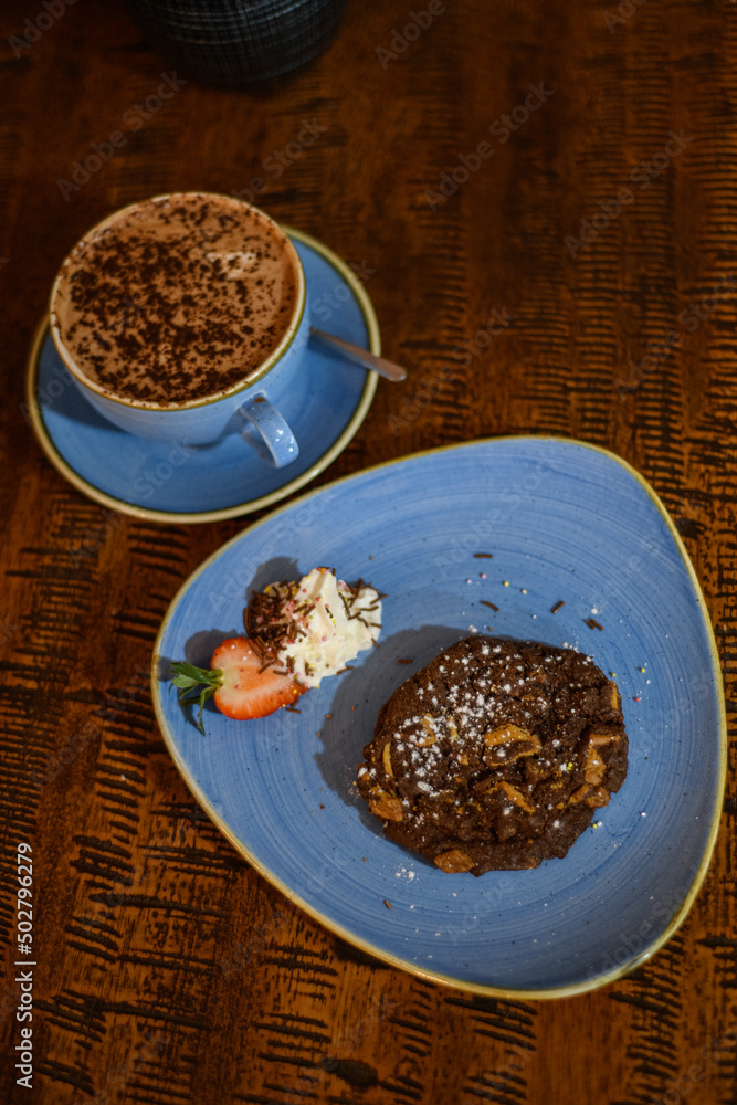 Overhead view of a chocolate and nut cookie with a hot chocolate on a table Overhead view of a chocolate and nut cookie with a hot chocolate on a table