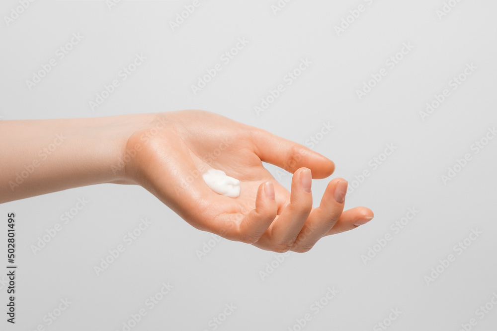 Handful of hand cream on a woman's hand. Photo on gray background.