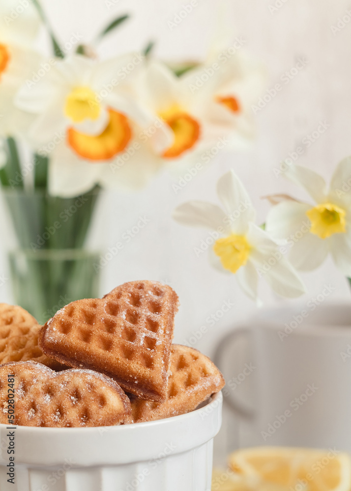 Fresh heart shapet waffles in a bowl on a white table.