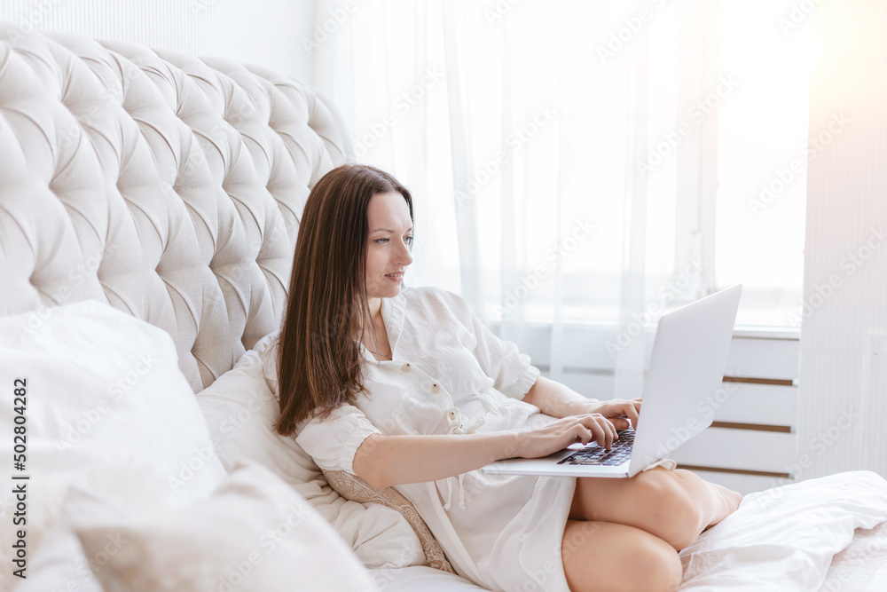 young woman with laptop sitting on the bed in her bedroom. young woman with laptop sitting on the bed in her bedroom.